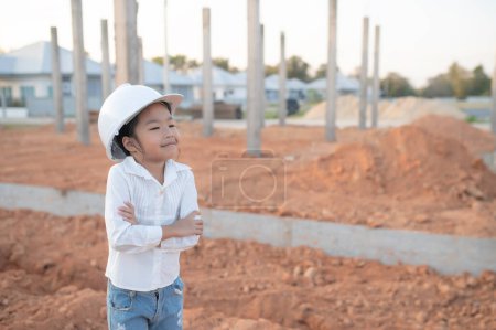 Téléchargez les photos : Ingénieur concept enfant, Asiatique petite fille porter ingénieur uniforme de travail sur le site du bâtiment - en image libre de droit