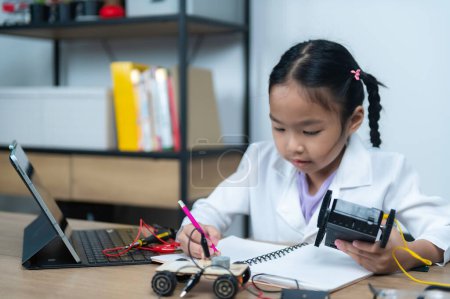 Téléchargez les photos : Asiatique petite fille construction et codage robot à la classe STIM, Fixation et réparation mécanicien jouet voiture - en image libre de droit