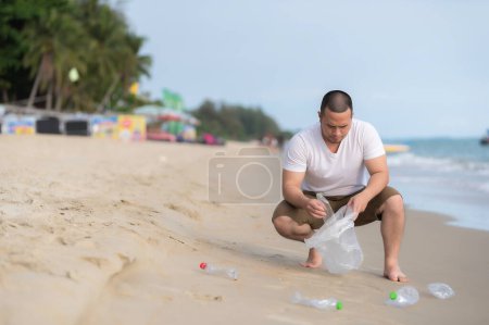 Téléchargez les photos : Asiatique homme garder les ordures à l'intérieur de la mer plage, les gens bénévoles garder la bouteille de plastique ordures - en image libre de droit