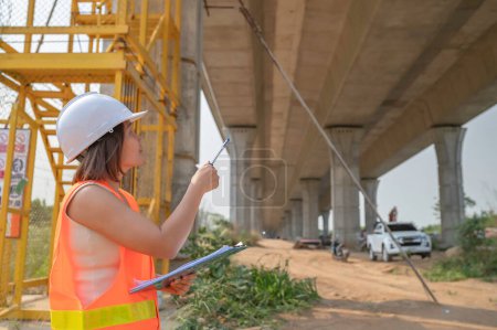 Foto de Una ingeniera asiática trabaja en una obra de construcción de puentes de autopista, Trabajadora civil inspeccionando trabajos de construcción de cruces - Imagen libre de derechos