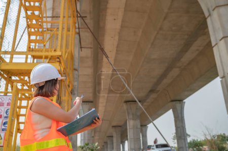 Foto de Una ingeniera asiática trabaja en una obra de construcción de puentes de autopista, Trabajadora civil inspeccionando trabajos de construcción de cruces - Imagen libre de derechos