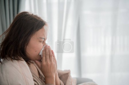 Foto de Asiática enferma mujer sentarse en el sofá estancia en casa, La mujer se sentía mal, quería acostarse y descansar, fiebre alta - Imagen libre de derechos