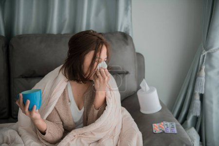 Photo for Asian sick woman sit on the sofa stay at home,The woman felt bad, wanted to lie down and rest,high fever - Royalty Free Image