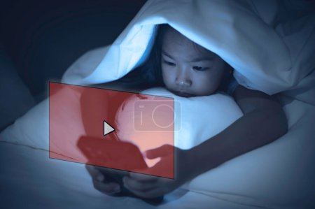Téléchargez les photos : Asian kid playing game on smartphone in the bed at night,The girl Addict social media - en image libre de droit