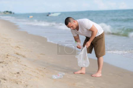 Foto de Hombre asiático mantener la basura en el interior de la playa de mar, la gente voluntaria mantener la basura botella de plástico - Imagen libre de derechos