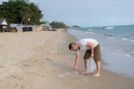 Téléchargez les photos : Asiatique homme garder les ordures à l'intérieur de la mer plage, les gens bénévoles garder la bouteille de plastique ordures - en image libre de droit