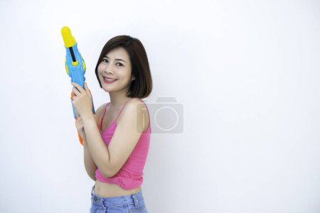 Téléchargez les photos : Asiatique femme sexy avec de l'eau de pistolet à la main sur fond blanc, Festival songkran jour à Thaïlande, Le meilleur de festival de thaï, Terre de sourire - en image libre de droit