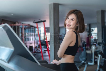 Téléchargez les photos : Belle femme asiatique jouer fitness dans la salle de gym, Thaïlande fille a un corps mince, Temps pour l'exercice, Les gens aiment la santé, Étirement du corps avant l'entraînement, Sport femme échauffement du corps, pousser avec haltère - en image libre de droit