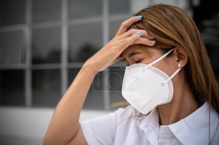 Téléchargez les photos : Femme asiatique porter N95 masque pour protéger la poussière pm 2.5, concept d'écologie. Allergie, maux de tête. danger aérien en ville. - en image libre de droit