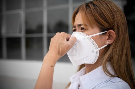 Foto de Mujer asiática usar máscara N95 para proteger el polvo pm 2.5, concepto de ecología. Alergia, dolor de cabeza. peligro de aire en la ciudad. - Imagen libre de derechos