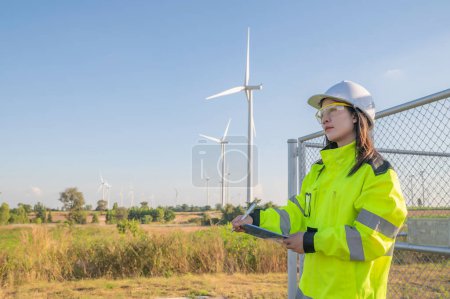 Photo for Asian woman engineers working and holding the report at wind turbine farm Power Generator Station on mountain,Thailand people,Technician at site of work - Royalty Free Image