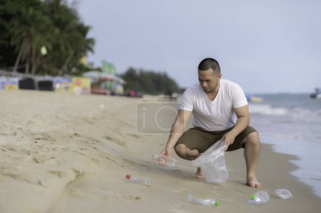 Foto de Hombre asiático mantener la basura en el interior de la playa de mar, la gente voluntaria mantener la basura botella de plástico - Imagen libre de derechos