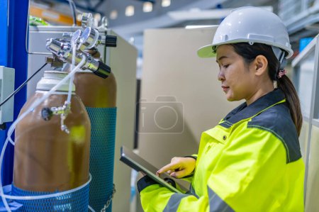 Photo for Asian engineer working at Operating hall,Thailand people wear helmet  work,He worked with diligence and patience,she checked the valve regulator at the hydrogen tank. - Royalty Free Image