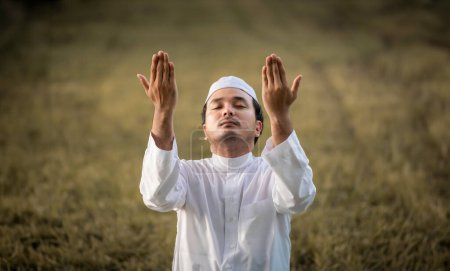 Téléchargez les photos : Un jeune homme musulman asiatique priant au coucher du soleil, concept de festival Ramadan - en image libre de droit