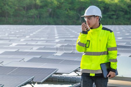 Foto de Ingeniero asiático trabajando en planta de energía solar flotante, energía renovable, técnico e inversor paneles solares comprobando los paneles en la instalación de energía solar - Imagen libre de derechos