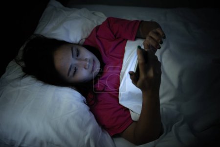 Photo for Asian woman playing game on smartphone in the bed at night,Thailand people,Addict social media - Royalty Free Image