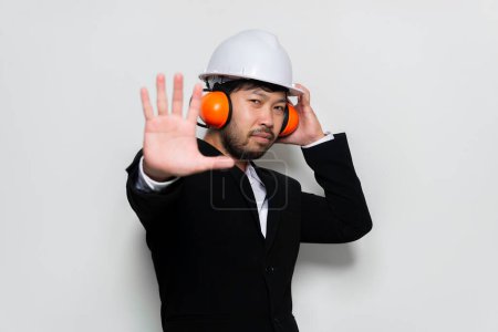 Téléchargez les photos : Ingénieur portant un casque de protection et insonorisation sur fond blanc - en image libre de droit