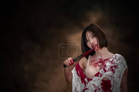 Foto de Retrato de mujer asiática maquillaje cara de fantasma. Escena de horror. Fondo aterrador. Cartel de Halloween. Tailandia gente. La señora tiene un hacha en la mano. Precioso concepto zombie - Imagen libre de derechos