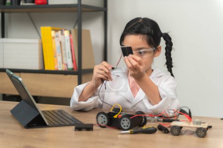 Photo for Asian littlle girl constructing and coding robot at STEM class. Fixing and repair mechanic toy car - Royalty Free Image