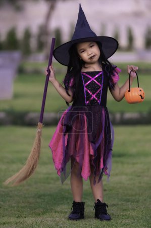 Téléchargez les photos : Asiatique mignon enfant féminin porter costume de sorcière avec pumkin. Concept de festival Halloween - en image libre de droit