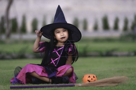 Téléchargez les photos : Asiatique mignon enfant féminin porter costume de sorcière avec pumkin. Concept de festival Halloween - en image libre de droit