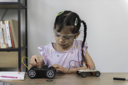 Photo for Asian littlle girl constructing and coding robot at STEM class. Fixing and repair mechanic toy car - Royalty Free Image