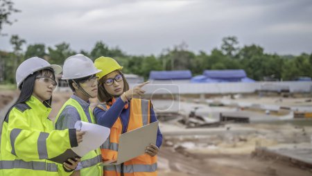 Photo for Young and senior Engineers discuss about work of large building under construction. Three people working on site of under construction - Royalty Free Image