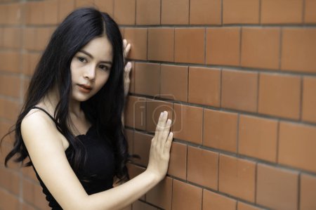 Téléchargez les photos : Portrait de fille hipster sur fond de mur de briques. Belle femme asiatique pose pour prendre une photo. Style Kawaii - en image libre de droit