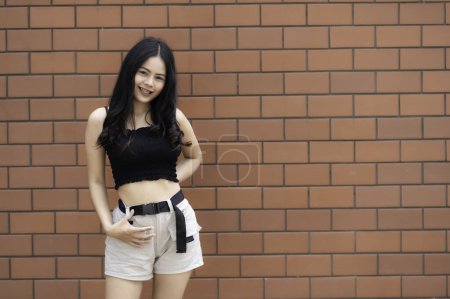 Foto de Retrato de chica hipster sobre fondo de pared de ladrillo. Hermosa mujer asiática posar para tomar una foto. Estilo Kawaii - Imagen libre de derechos