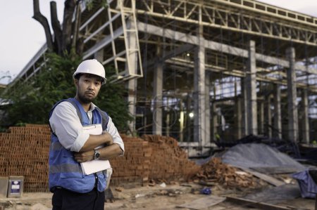 Téléchargez les photos : Ingénieur asiatique travaillant sur le site d'un grand projet de construction. Les Thaïlandais. Heures supplémentaires sur le chantier - en image libre de droit