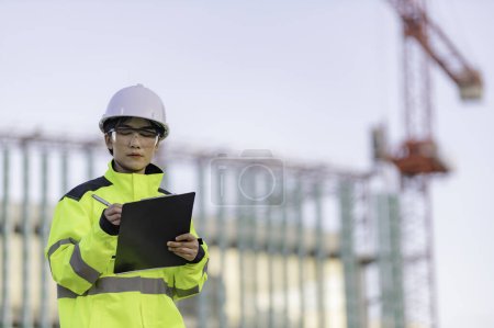 Photo for Asian engineer working at site of a large building project. Thailand people. Work overtime at construction site - Royalty Free Image