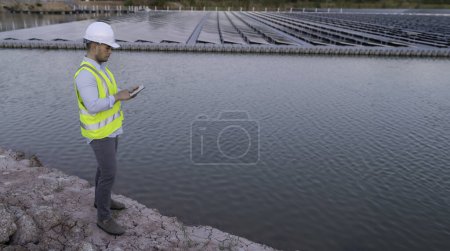 Téléchargez les photos : Ingénieur asiatique travaillant à la ferme solaire flottante. Les énergies renouvelables. Technicien et investisseur panneau solaire de contrôle des panneaux à l'installation d'énergie solaire - en image libre de droit