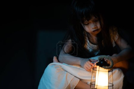 Téléchargez les photos : Sad child ghost at night. Halloween Festival concept. Friday 13th. Horror movie scene. A girl with doll - en image libre de droit
