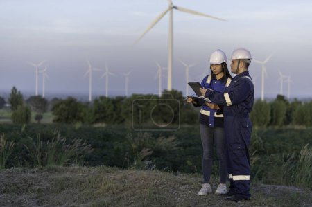 Téléchargez les photos : Deux ingénieurs travaillent et tiennent le rapport à la centrale éolienne de la montagne. Les Thaïlandais. Technicien homme et femme discutent du travail - en image libre de droit