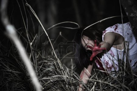 Foto de Retrato de mujer asiática maquillaje cara de fantasma. Escena de horror. Fondo aterrador. Cartel de Halloween. Tailandia gente. La señora tiene un hacha en la mano. Precioso concepto zombie - Imagen libre de derechos