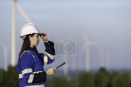 Photo for Engineer working and holding the report at wind turbine farm Power Generator Station on mountain. Thailand people - Royalty Free Image