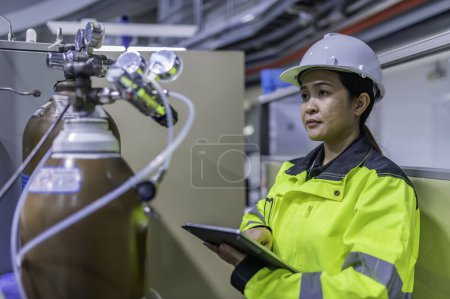 Photo for Asian engineer working at Operating hall. Thailand people wear helmet  work. He worked with diligence and patience, she checked the valve regulator at the hydrogen tank. - Royalty Free Image