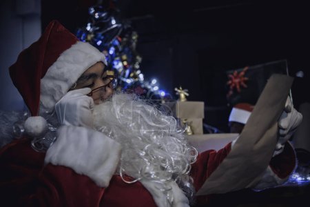Foto de Retrato de Santa Claus feliz leyendo un libro. Tailandia la gente usa vestido de Santa Claus. Envió felicidad a los niños. Feliz navidad. Bienvenido al invierno - Imagen libre de derechos