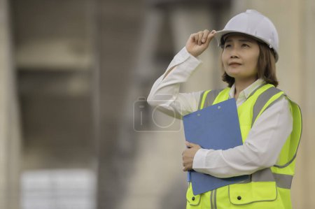 Foto de Una ingeniera asiática trabaja en una obra de construcción de puentes de autopista. Trabajadores civiles que inspeccionan trabajos de construcción de cruces - Imagen libre de derechos