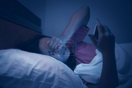 Photo for Asian woman playing game on smartphone in the bed at night. Thailand people. Addict social media - Royalty Free Image