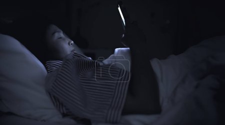Photo for Asian woman playing game on smartphone in the bed at night. Thailand people. Addict social media - Royalty Free Image