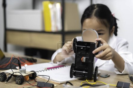 Téléchargez les photos : Asiatique petite fille construction et codage robot à la classe STIM. Fixation et réparation mécanicien jouet voiture - en image libre de droit