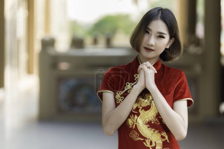 Téléchargez les photos : Portrait belle femme asiatique en robe Cheongsam. Les Thaïlandais. Bonne année chinoise concept. Heureuse dame asiatique en robe traditionnelle chinoise - en image libre de droit