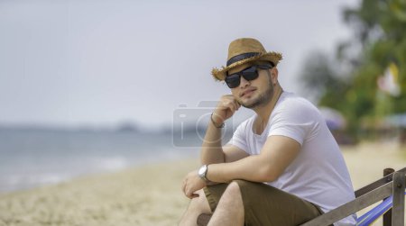 Photo for Asian man sitting chair on sea beach. Relax time at summer - Royalty Free Image