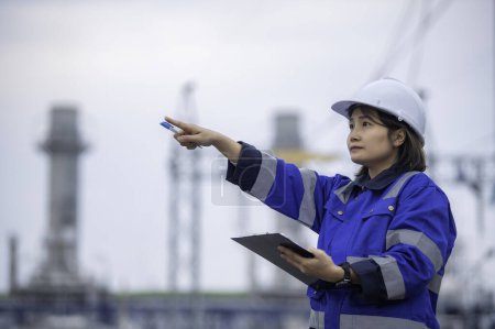Foto de Mujer asiática ingeniera petroquímica que trabaja en la fábrica de plantas de refinería de petróleo y gas. La mujer trabajadora ingeniero de control de trabajo en la planta de energía de fabricación de la industria energética - Imagen libre de derechos