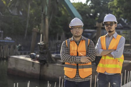 Photo for Construction engineers working on a bridge construction site over a river. Civil engineers supervising work. Foremen inspects work at a construction site. Discuss technical problems together - Royalty Free Image