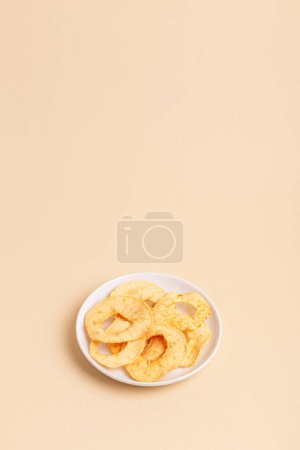 Minimalist composition with apple chips in a white ceramic plate on a light beige background. Healthy sweet snack.