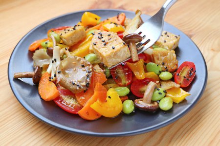 Téléchargez les photos : Fourchette Scooping Velvet Pioppini Champignon et cubes de tempeh rôtis de salade végétalienne colorée - en image libre de droit