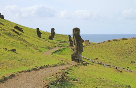 Group of abandoned massive Moai statues scattered on the slope of Rano Raraku volcano, historic Moai quarry on Easter Island, Chile