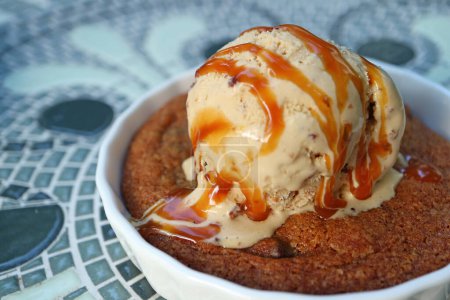 Closeup Mouthwatering Texture of Warm Cookie Topped with Ice Cream and Salted Caramel Sauce